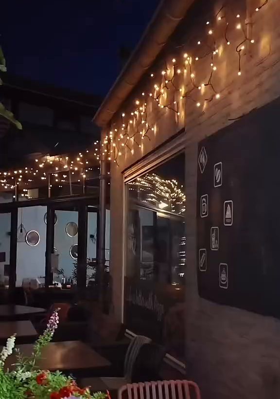 Het terras 's avonds, met lichtjes langs de gevel